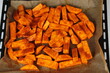Sliced raw sweet potato with oil and spices on the baking paper, oven pan. Cooking sweet potato or batatas recipe in an oven
