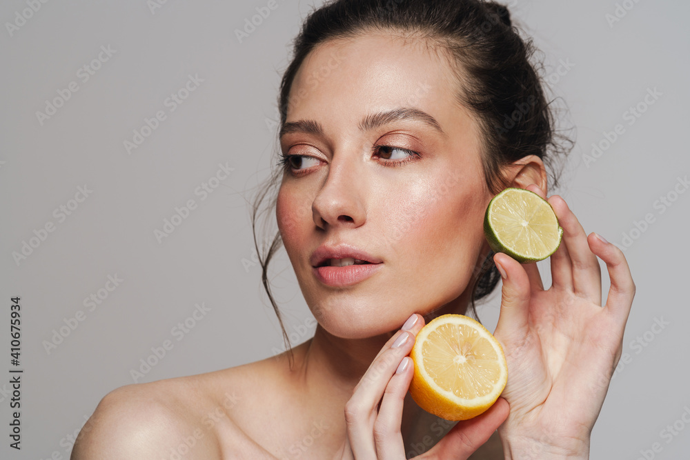 Beautiful half-naked woman posing with citruses on camera - obrazy, fototapety, plakaty 