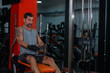 © qunica.com - Fitness training in sport gym of active male with beard sitting and pulling heavy weight on exercise equipment