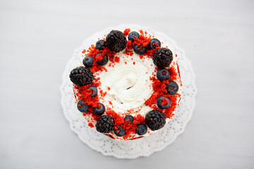 Wall Mural - homemade red velvet cake decorated with berries on a light wooden background