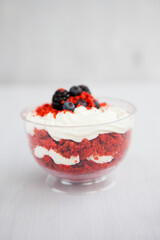 Wall Mural - homemade portioned dessert red velvet decorated with berries on a light wooden background