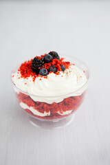 Wall Mural - homemade portioned dessert red velvet decorated with berries on a light wooden background