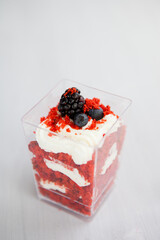 Wall Mural - homemade portioned dessert red velvet decorated with berries on a light wooden background