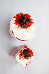 Wall Mural - homemade portioned dessert red velvet decorated with berries on a light wooden background