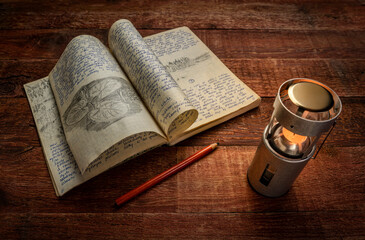 Wall Mural - Vintage expedition journal on a picnic table with a candle lantern. Travel log from paddling trip across north eastern Poland in August 1974 - handwriting and drawing in pencil.