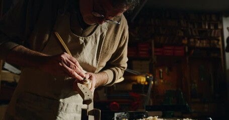 Wall Mural - Cinematic shot of experienced master artisan luthier painstaking detail work on fine quality wood violin in creative workshop.Concept of spiritual instrument,handmade, art, orchestra, artisan, passion