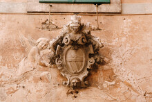 A Bas-relief On The Facade Of A Building In The Old Town Of Kotor In Montenegro. Knight's Shield And Armor, Dove And Angels.
