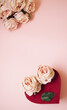 Love at first sight, heart and bouquet of pink roses on pastel pink background. Love concept. Flat lay.