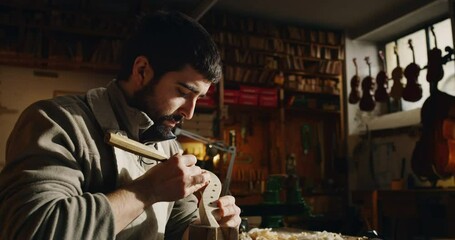 Poster - Cinematic shot of young master artisan luthier painstaking detail work on fine quality wood violin in creative workshop.Concept of spiritual instrument,handmade, art, orchestra, artisan, passion