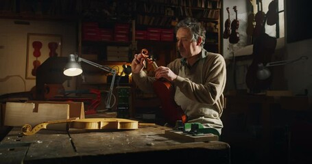 Poster - Cinematic shot of master artisan luthier working on creation of handmade fine quality wood violin in creative workshop. Concept of spiritual instrument, handmade, art, orchestra, artisan, music.