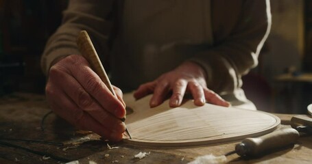 Wall Mural - Cinematic shot of master artisan luthier working on creation of handmade fine quality wood violin in his creative workshop. Concept of spiritual instrument, handmade, art, orchestra, artisan, music.