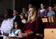 © JackF - Friendly biracial family spending time together in cinema. Selective focus of young european woman sitting with cute preteen girl and aframerican man, absorbedly watching movie