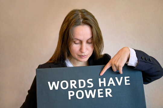 The girl woman stands and points her finger at the inscription on the black board Words have power
