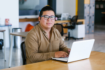 Wall Mural - plus size latin man working on laptop in office in Mexico city