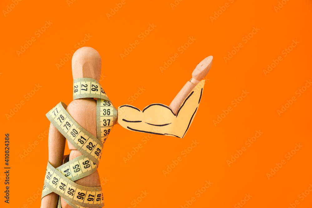 Wooden mannequin with measuring tape on color background