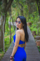 Portrait Asian woman in a blue suit standing on a wooden coastal bridge with a nature background.