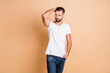 © deagreez - Photo of young handsome guy masculine confident look empty space hand in pocket isolated over beige color background
