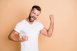 © deagreez - Photo of young excited man happy positive smile fun joy enjoy fists hands celebrate win victory goal isolated over beige color background