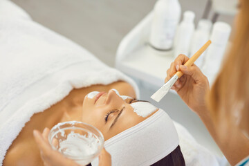 Wall Mural - Cosmetologist putting mask for facial cleaning for relaxing woman in beauty salon