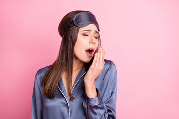 Wall Mural - Photo portrait of sleepy girl yawning covering mouth with hand isolated on pastel pink colored background