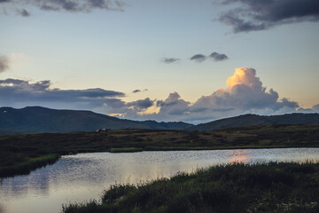 Wall Mural - scenic sunset landscape with yellow big cloud in form of explosion above mountain lake. awesome gian