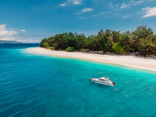 Tropical island with beach, turquoise sea and white boat. Aerial view.