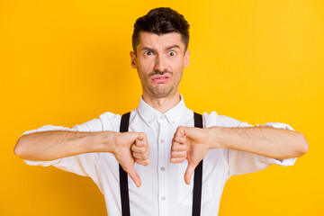 Wall Mural - Photo portrait of unhappy dissatisfied guy showing dislike sign thumb down grimacing isolated on vibrant yellow color background