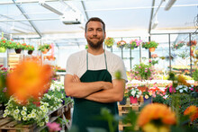 Happy Worker Growing Flowers In A Greenhouse Of A Flower Shop