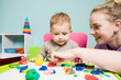 © oksix - The young teacher and cute baby boy play with plasticine
