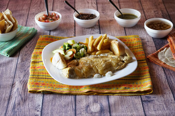 Canvas Print - Closeup shot of delicious grilled chicken with vegetables and fries on the colorful tablecloth