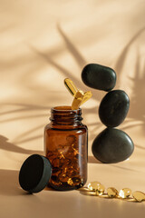 Wall Mural - The pills fall into the jar. Levitation style. Omega 3 tablets on a beige background. Black stones for acapuncture