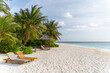 Traumhafter Strand mit Palmen und Sonnenliegen auf einer kleinen Insel auf den Malediven