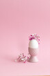 Easter eggin a pink vase with flowers on pink . cupy space.
