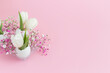 Easter holiday decoration in eggshell white tulips and pink gypsophila and two white eggs on pink pastel background. copy space.