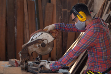 Skilled carpenter cutting a piece of wood in his woodwork workshop