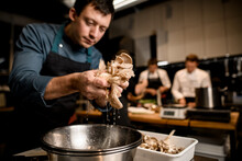Man Chef Holds Oyster Mushrooms Over Bowl On Kitchen
