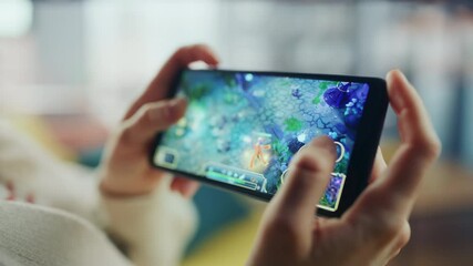 Poster - Close Up on Hands Playing an RPG Strategy Video Game on a Horizontally Held Smartphone at Home Living Room. Feminine Hands Tapping the Mobile Phone Screen with a Colorful Game Over the Internet.