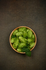 Wall Mural - Wooden bowl of fresh green hops on table