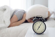 © Hazal - Irritated young woman putting her alarm clock off in the morning with soft morning light. Relaxing concept.