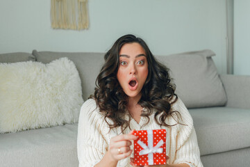 Young woman opens a red gift box. Portrait of a happy woman. Holidays. Valentine's Day.