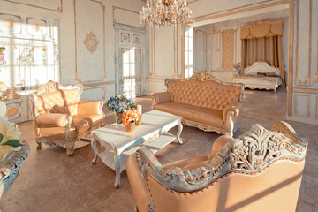 rich apartment interior with golden baroque decorations on the walls and luxury furniture. the room is flooded with the rays of the setting sun