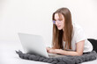 © Andriy Medvediuk - A smiling young girl in glasses sits with a laptop. Education, remote work and blogging. Isolated on a white background.