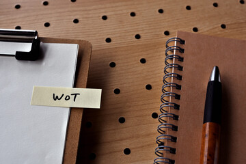 Poster - There is a notebook, a pen, and a clipboard with a sticky note stuck to it that says WoT written on it. It was an abbreviation for Web of Things.