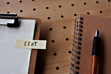 Poster - There is a notebook, a pen, and a clipboard with a sticky note stuck to it that says IIoT written on it. It was an abbreviation for Industrial Internet of Things.