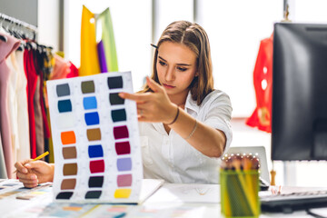 Wall Mural - Portrait of young beautiful pretty woman fashion designer stylish sitting and working.Attractive young girl use desktop conputer and colorful fabrics at fashion design studio