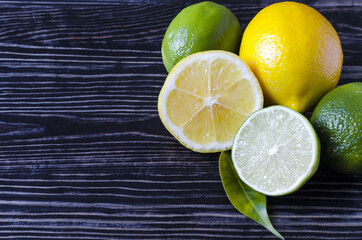 fresh green limes and yellow lemons on a wooden background of copi space