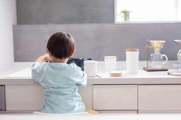 Wall Mural - 白いキッチンで男の子が青い鍋で料理をしている　boy kitchen 