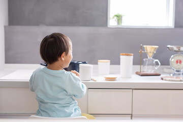 Wall Mural - 白いキッチンで男の子が青い鍋で料理をしている　boy kitchen 