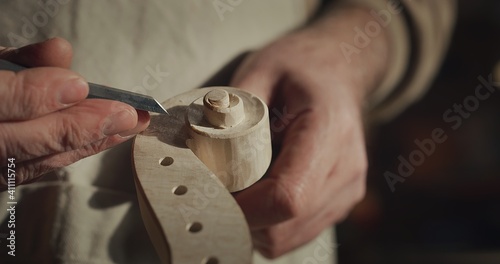 Cinematic macro of experienced master artisan luthier painstaking detail work on fine quality wood violin in creative workshop.Concept of spiritual instrument,handmade, art, orchestra, artisan,passion