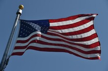 The American Flag Fluttering In A Semicircle On A Blue Background.